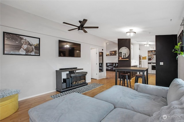 living room with ceiling fan, a fireplace, and hardwood / wood-style floors