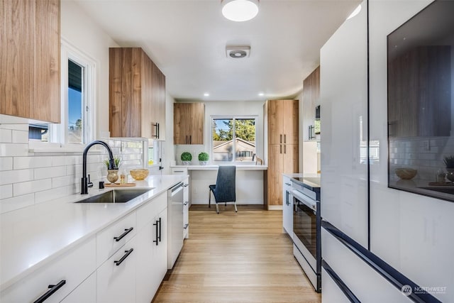 kitchen featuring sink, white cabinetry, tasteful backsplash, appliances with stainless steel finishes, and light hardwood / wood-style floors