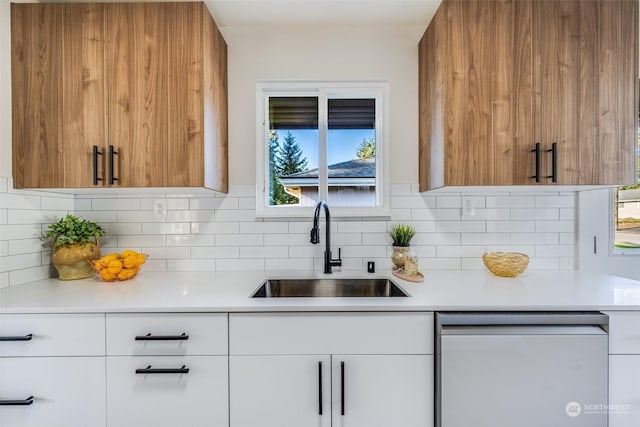 kitchen featuring dishwasher, white cabinetry, sink, and backsplash