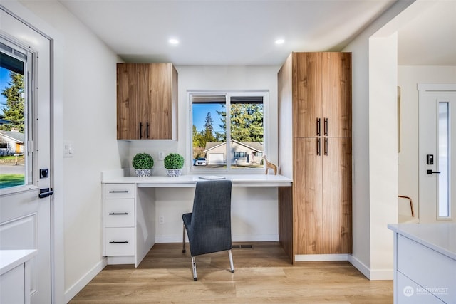 office area with built in desk and light wood-type flooring