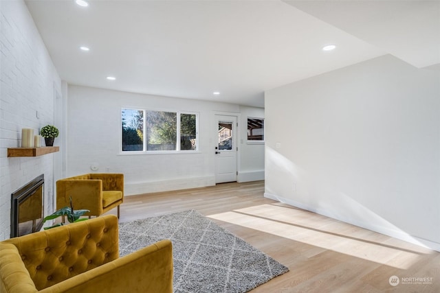 living room featuring hardwood / wood-style flooring, a large fireplace, and brick wall