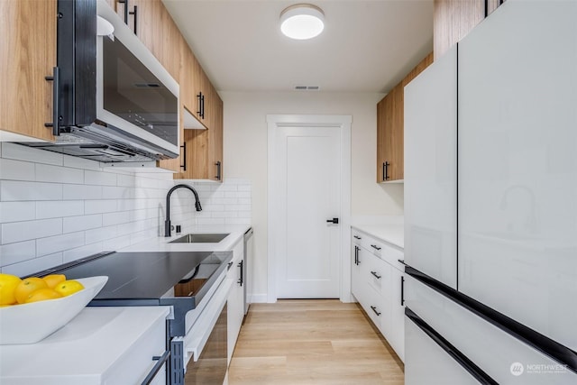 kitchen with sink, light hardwood / wood-style flooring, white cabinetry, electric range oven, and decorative backsplash