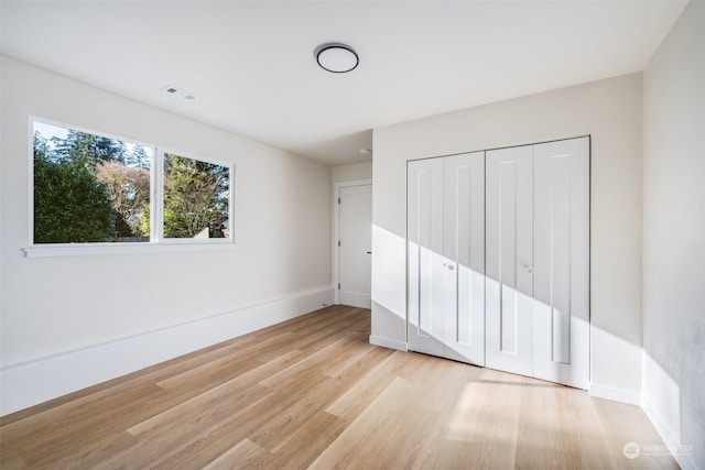 unfurnished bedroom featuring light wood-type flooring and a closet