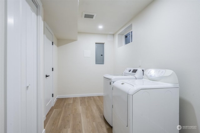 washroom with washing machine and dryer, electric panel, and light wood-type flooring