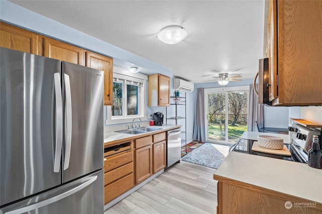 kitchen with a wealth of natural light, appliances with stainless steel finishes, sink, and a wall mounted AC