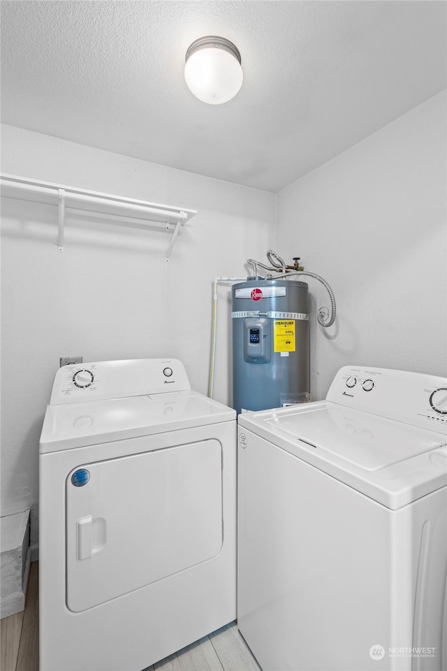 laundry area with washing machine and clothes dryer, a textured ceiling, and secured water heater