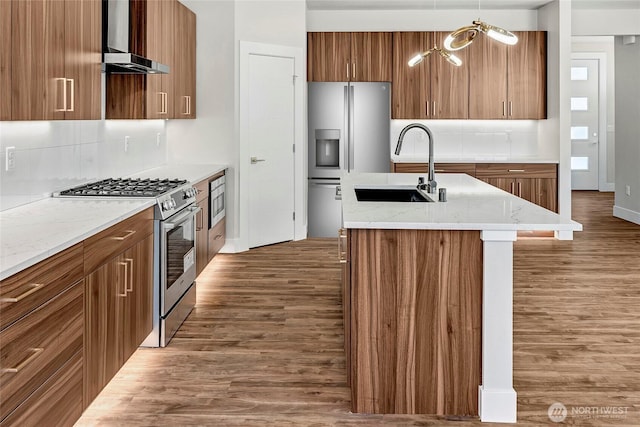 21402 39th Dr SE Unit A, Bothell, WA 98021 - kitchen featuring stainless steel appliances, a sink, wall chimney exhaust hood, wood finished floors, and brown cabinets