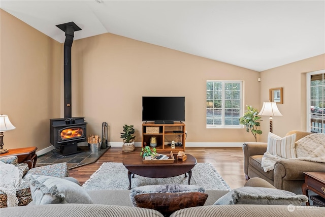 living room with hardwood / wood-style flooring, vaulted ceiling, and a wood stove