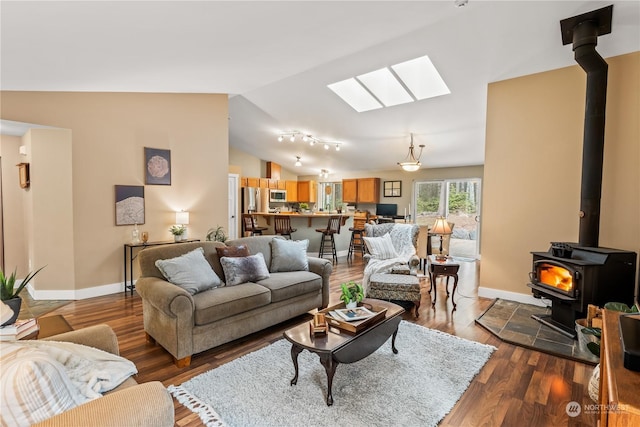 living room with dark wood-type flooring, lofted ceiling with skylight, and a wood stove