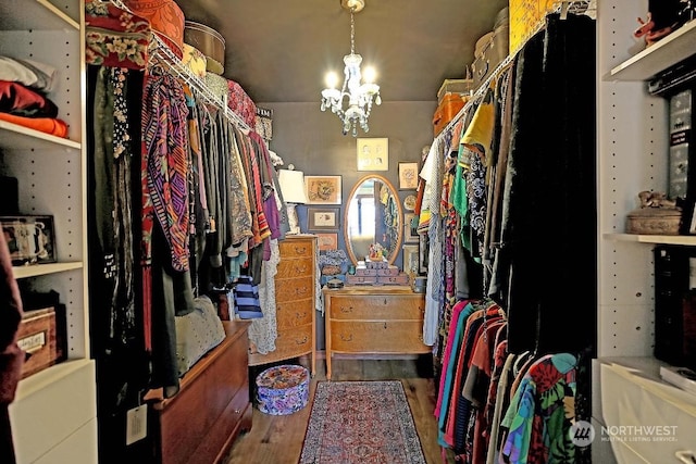 walk in closet with a chandelier and wood finished floors