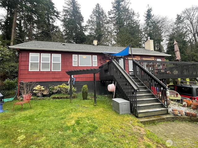 back of property featuring a shingled roof, stairway, a deck, and a yard