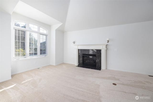 unfurnished living room featuring lofted ceiling, a premium fireplace, and light carpet