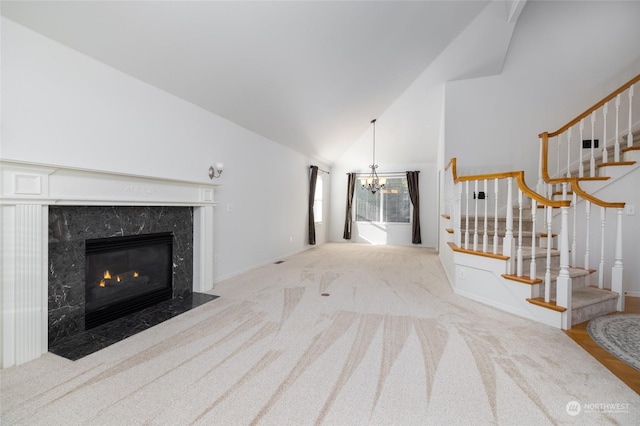 living room with light colored carpet, a high end fireplace, high vaulted ceiling, and a chandelier