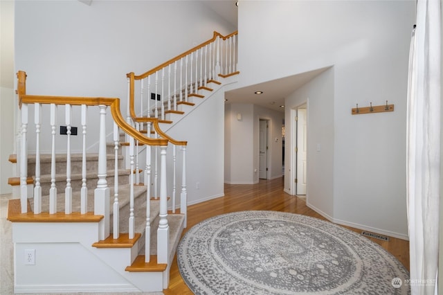 stairway with hardwood / wood-style flooring and a high ceiling