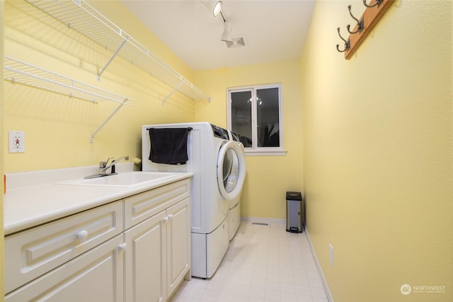 laundry room with track lighting, cabinets, washer and clothes dryer, and sink