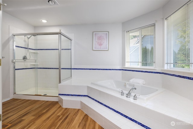 bathroom with wood-type flooring and shower with separate bathtub