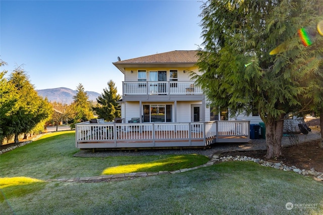 rear view of property featuring a balcony, a yard, and a deck with mountain view