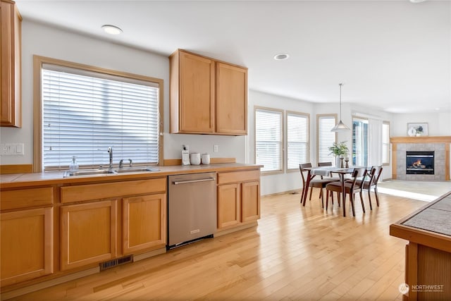 kitchen featuring dishwasher, light countertops, a sink, and visible vents