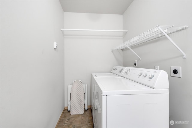 laundry room with washing machine and dryer, laundry area, stone finish flooring, and baseboards