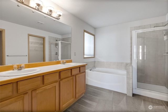 bathroom with a stall shower, double vanity, a sink, and a bath