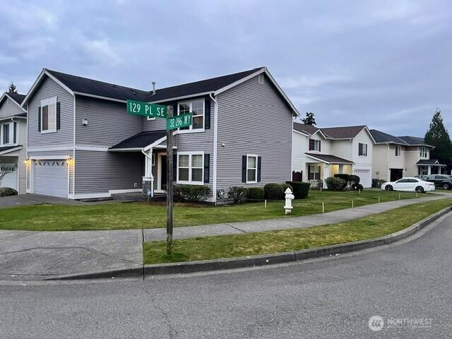 view of front of property featuring a garage, driveway, a front yard, and a residential view