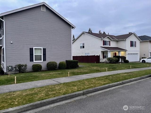 view of home's exterior featuring driveway, a lawn, an attached garage, and fence