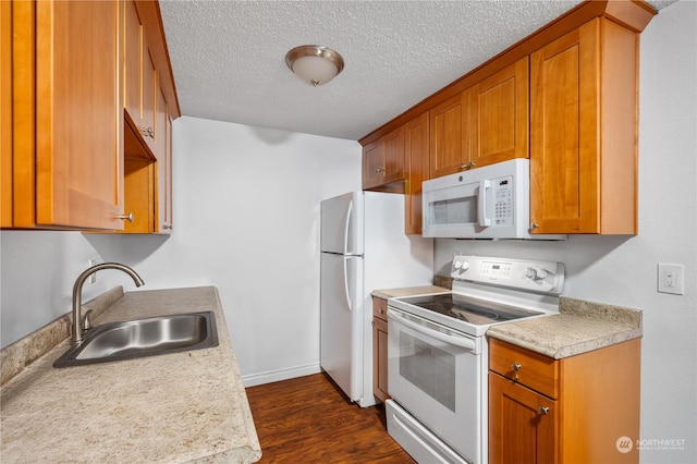 kitchen featuring dark hardwood / wood-style flooring, sink, white appliances, and a textured ceiling