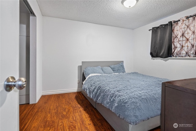 bedroom featuring dark wood-type flooring and a textured ceiling