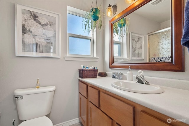 bathroom featuring vanity, a shower with shower door, and toilet