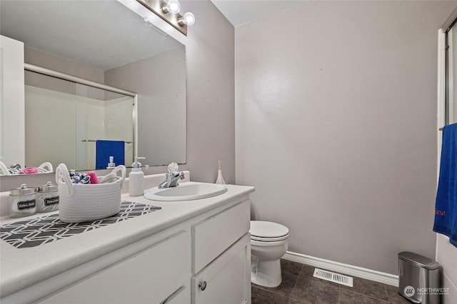 bathroom featuring a shower with door, vanity, and toilet