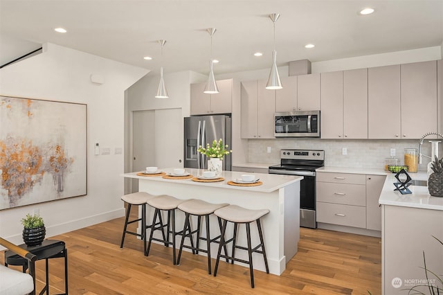 kitchen featuring light hardwood / wood-style flooring, stainless steel appliances, a center island, tasteful backsplash, and decorative light fixtures