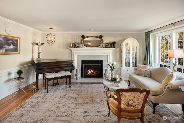 living area featuring ornamental molding, a high end fireplace, and light hardwood / wood-style flooring