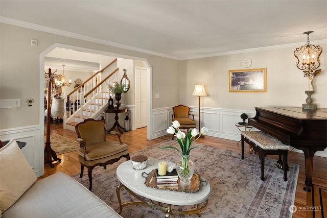 living room with ornamental molding, a chandelier, and light wood-type flooring