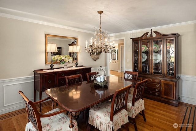 dining area featuring ornamental molding, light hardwood / wood-style floors, and a notable chandelier