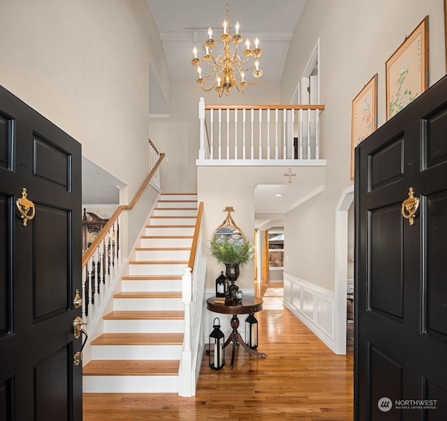 entryway featuring an inviting chandelier, a high ceiling, and light wood-type flooring