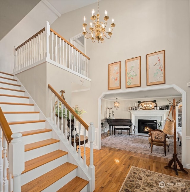 stairway with a notable chandelier, wood-type flooring, and a high ceiling