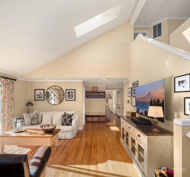 living room featuring crown molding, vaulted ceiling with skylight, and light hardwood / wood-style flooring