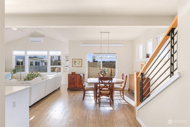 dining area with a wall mounted air conditioner, beam ceiling, and light hardwood / wood-style flooring