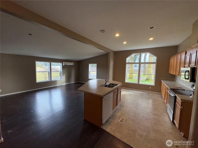 kitchen featuring a sink, open floor plan, light countertops, appliances with stainless steel finishes, and an island with sink