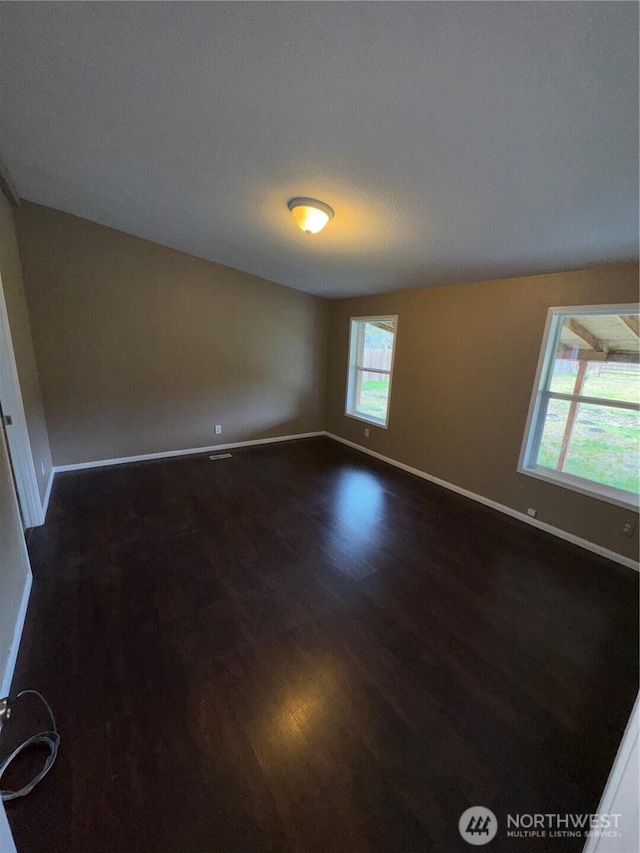 empty room featuring dark wood finished floors and baseboards