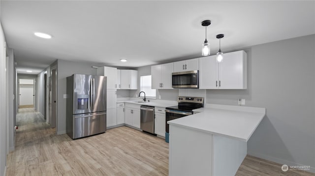 kitchen with pendant lighting, light hardwood / wood-style flooring, appliances with stainless steel finishes, white cabinets, and kitchen peninsula