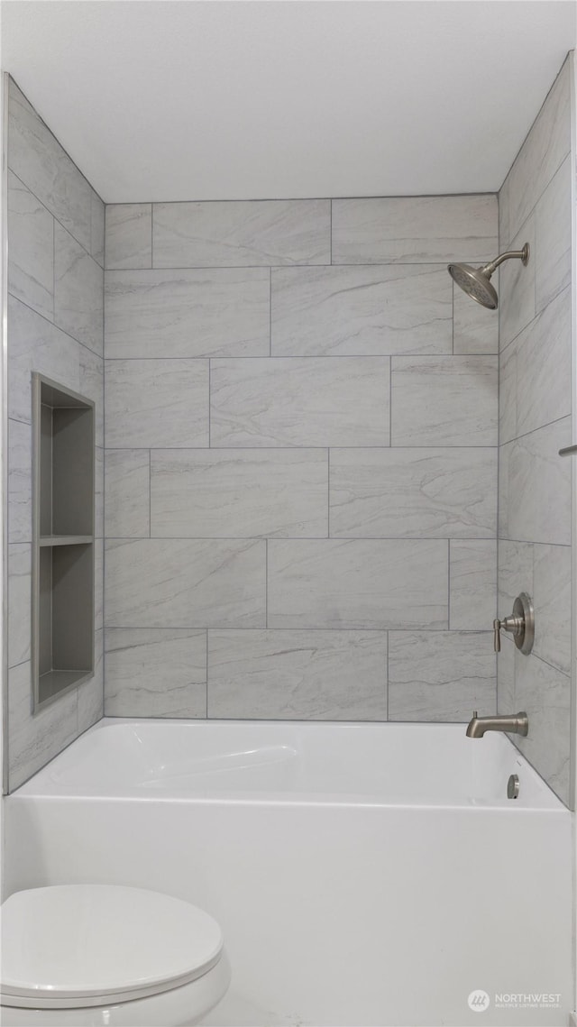 bathroom with tiled shower / bath combo and toilet