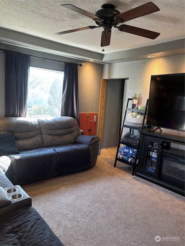 living room with carpet floors, a ceiling fan, a textured ceiling, and a textured wall