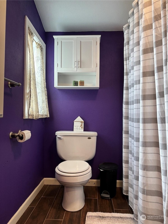 full bathroom featuring toilet, a shower with curtain, wood tiled floor, and baseboards