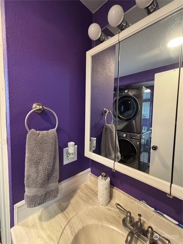 bathroom with stacked washer and dryer and a sink