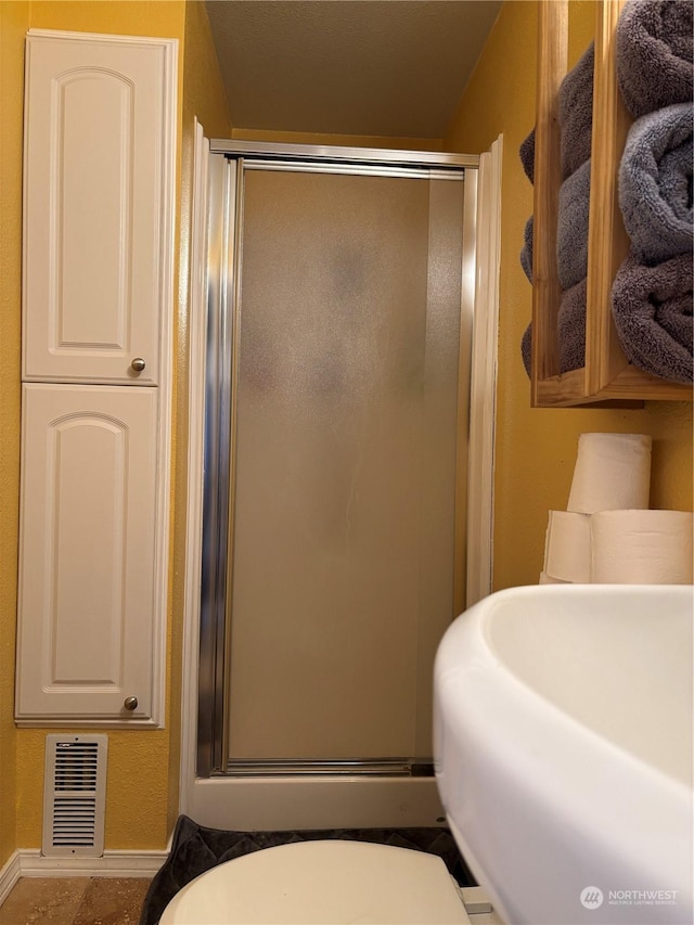 full bath featuring toilet, a shower stall, and visible vents