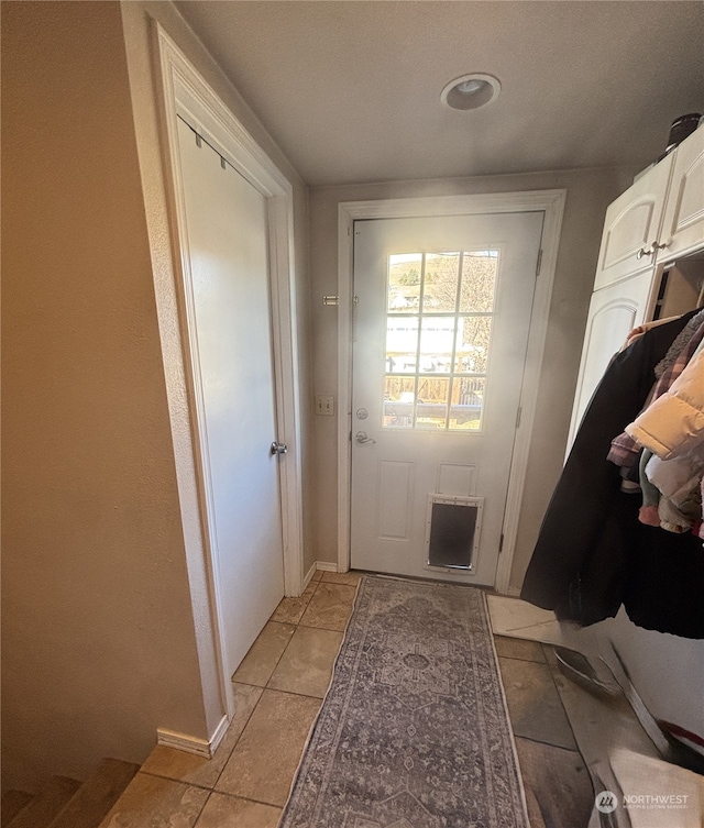 doorway with light tile patterned floors, visible vents, and baseboards