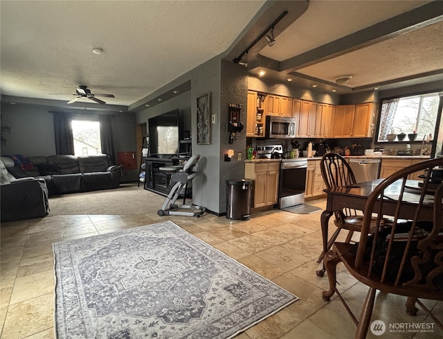 kitchen with a textured ceiling, a sink, a ceiling fan, appliances with stainless steel finishes, and backsplash