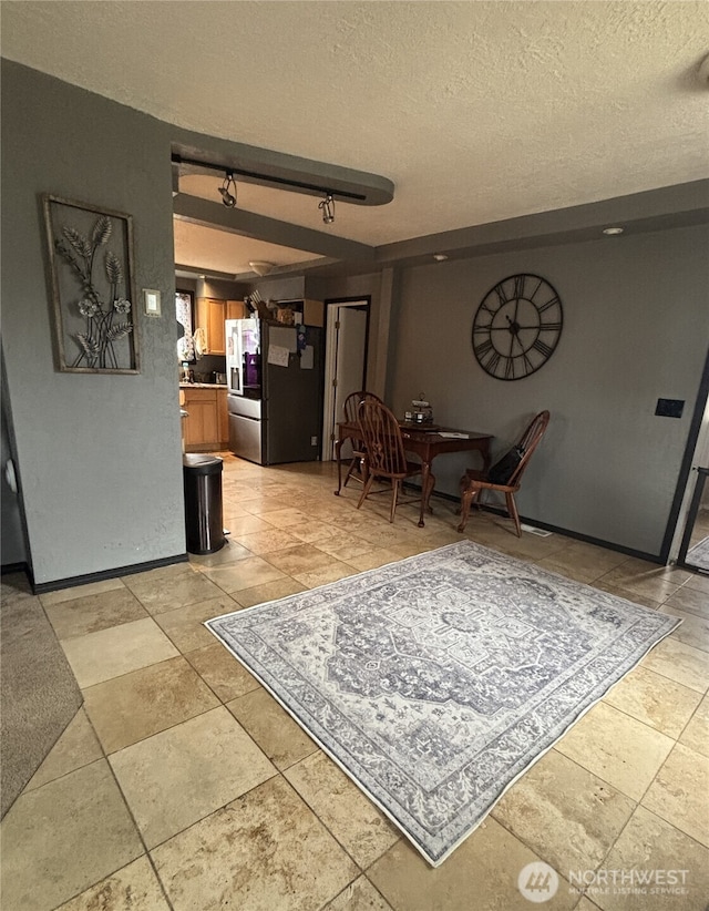 dining room featuring rail lighting, a textured ceiling, and baseboards