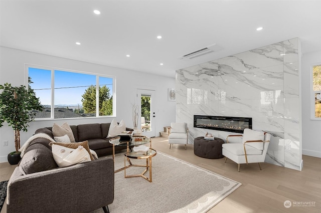 living room featuring a wealth of natural light, a fireplace, and light wood-type flooring